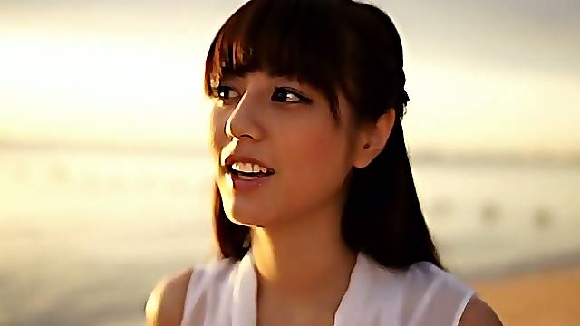 Slim Asian girl Yumi Sugimoto walks on a beach wearing white dress