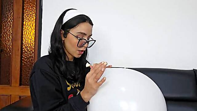 Marianna blows a white balloon full of red kisses to make it pop