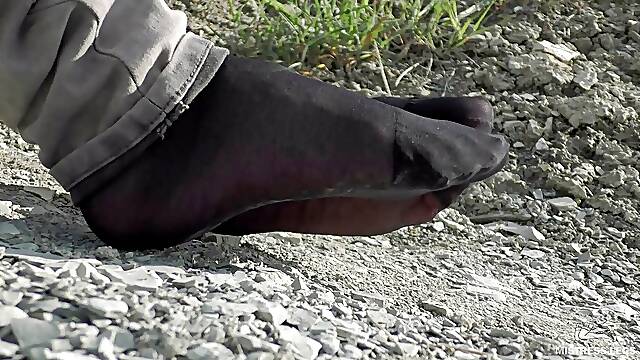 Jeans feet in black nylon socks on the seashore